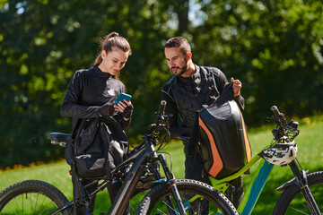 A sweet couple, equipped with bicycles and engrossed in coordinating their journey, checks their...