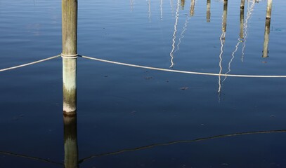 Reflection of boat masts and wooden pole in the water