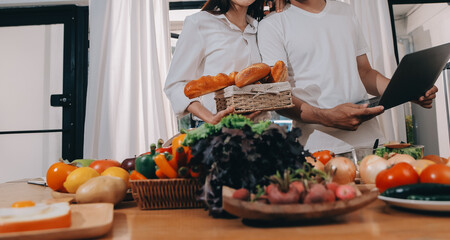 Handsome man sitting near his wife at kitchen. Family couple see social media, surf the web while...