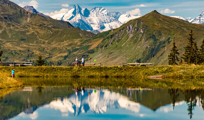 Alpine summer view with reflections and hikers at Lake Spiegelsee, Mount Fulseck, Dorfgastein, St....