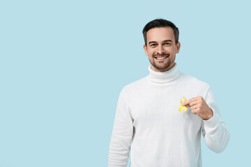 Handsome adult man with yellow ribbon on blue background. Suicide, endometriosis, bone cancer concept