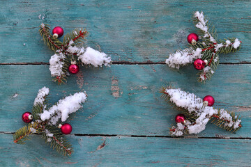 Weihnachtlicher Hintergrund Tannenzweige mit Christbaumkugeln und Schnee auf Holz