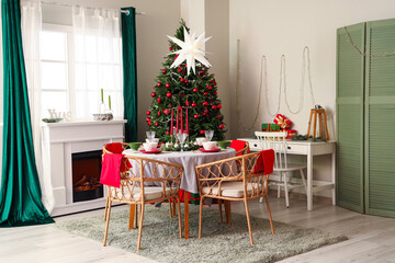 Interior of festive room with Christmas tree, decorations, fireplace and served dining table