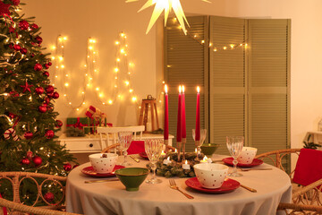Interior of festive room with Christmas tree, decorations and served dining table at evening
