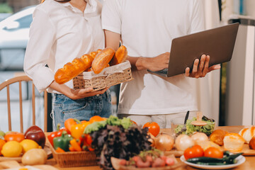 Handsome man sitting near his wife at kitchen. Family couple see social media, surf the web while...