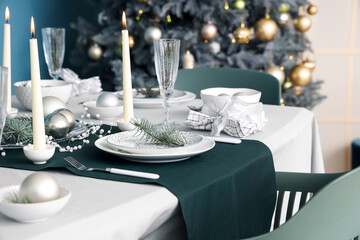 Beautiful table setting with burning candles and Christmas decorations in dining room, closeup