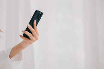 Happy young female in casual clothes smiling and looking at camera while using laptop on bed in bedroom at home