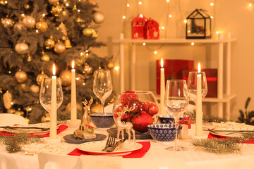Festive table setting with burning candles and Christmas decorations at evening, closeup