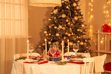 Festive table setting with burning candles and Christmas decorations at evening, closeup