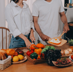 Handsome man sitting near his wife at kitchen. Family couple see social media, surf the web while sitting at kitchen table with generic laptop. Couple working with laptop at home