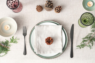 Christmas table setting with fir branches, burning candles and pine cones, top view