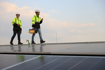Two special Electrical engineers in safety suits worked and checked the solar system on the roof after installing,  walking on the roof against the blue sky and photovoltaic panel.