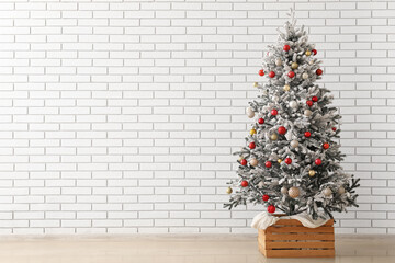 Beautiful Christmas tree decorated with different balls near light brick wall