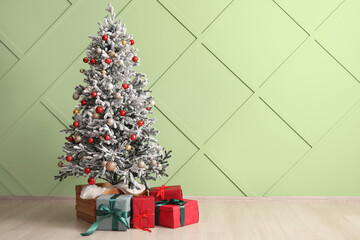 Christmas tree with beautiful gift boxes near color wall