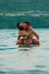 A romantic young couple sharing a passionate kiss amidst the serene beauty of the ocean at sunset.