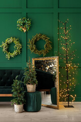 Fototapeta na wymiar Interior of festive living room with sofa, mirror, mini Christmas trees and decorations