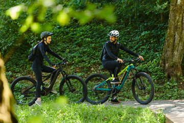 A blissful couple, adorned in professional cycling gear, enjoys a romantic bicycle ride through a park, surrounded by modern natural attractions, radiating love and happiness