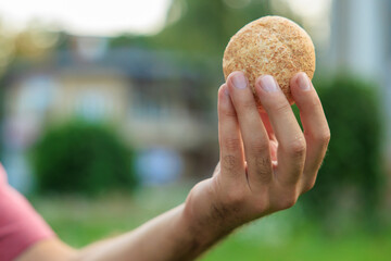 Guy's hand holds mini bread, snack and fast food concept. Selective focus on hands with blurred...