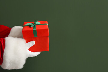 Santa hands with gift box on green background, closeup