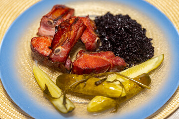 Traditional rustic Brazilian food, black rice, smoked pork ribs and pickles