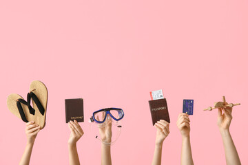Female hands with beach accessories, passports and credit card on pink background
