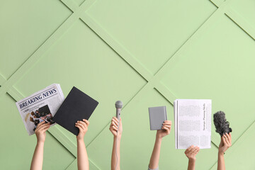 Female hands with newspapers, microphones and notebooks against color wall