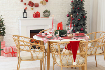 Festive Christmas dinner table setting with ornaments and fir branches in light dining room