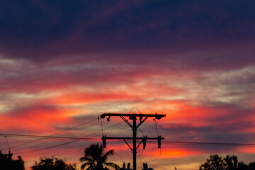 Silhouette of high voltage post with orange sky background at sunset.