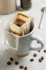 The process of brewing a bag Drip coffee into a cup on a gray background. A quick way to prepare a tasty and aromatic drink. Vertical orientation. Selective focus