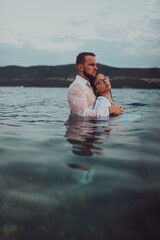 A symbolic and emotionally connected couple tenderly embraces against the backdrop of a serene sea, bathed in the warm hues of a breathtaking sunset