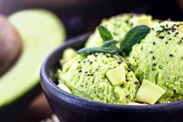 Homemade organic green avocado ice cream ready to eat, with mint leaf decorating.