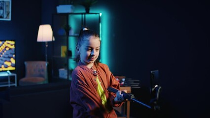 Smartphone on selfie stick used by talented gen z kid in dark room doing viral dance choreography, creating content to generate views and engagement from other online children
