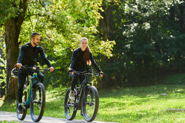 Fototapeta premium A blissful couple, adorned in professional cycling gear, enjoys a romantic bicycle ride through a park, surrounded by modern natural attractions, radiating love and happiness