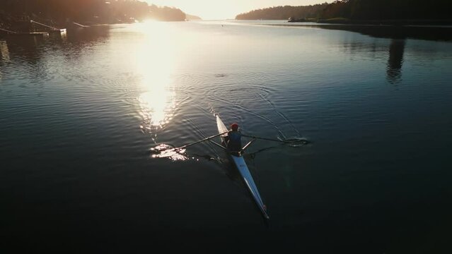 Aerial view at dawn, a lone rower training in a sports rowing boat in the ocean.