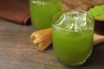 Glass of delicious iced green matcha tea on wooden table, closeup. Space for text