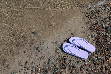 Stylish violet flip flops on beach pebbles, above view. Space for text