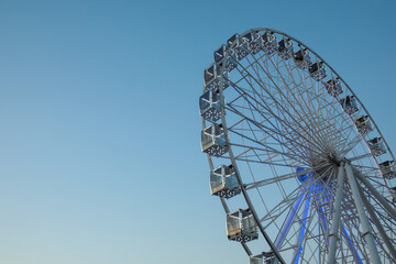Big Ferris wheel against light blue sky, low angle view. Space for text