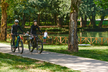 A blissful couple, adorned in professional cycling gear, enjoys a romantic bicycle ride through a park, surrounded by modern natural attractions, radiating love and happiness