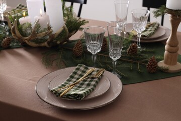Christmas table setting with burning candles and other festive decor