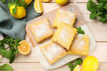 Tasty lemon bars with powdered sugar and mint on wooden table, flat lay