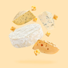 Different kinds of cheese falling on beige background