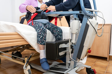 A care staff using a power assist to lifts a patient at nursing home. High quality photo