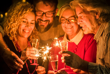 group of two seniors and two adults together having fun with sparlers the new year to celebrate -...