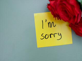 Top view of words i'm sorry written on sticky note with roses
