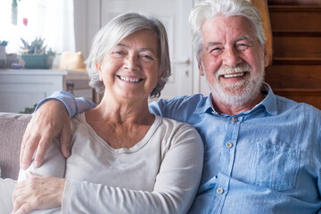 Portrait of happy middle aged retired family couple relaxing on cozy sofa at home. Smiling sincere...