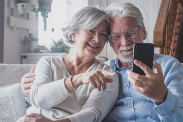 Smiling sincere mature older married family couple holding mobile video call conversation with friends, enjoying distant communication with grown children, using smartphone applications at home..