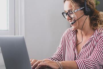 Attractive caucasian woman sit at home office room wearing headset take part in educational webinar...
