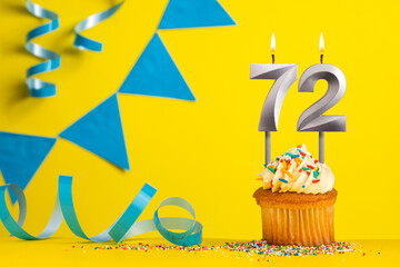Lighted birthday candle number 72 - Yellow background with blue pennants
