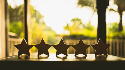 Businessman hand picking up model star on wooden table, Five star shape. The best excellent...