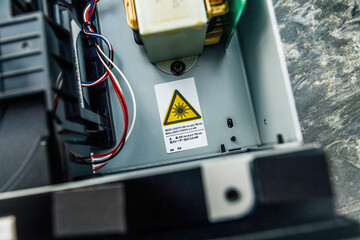 An image of a laser device with a warning sticker indicating the hazard, with wires and components...